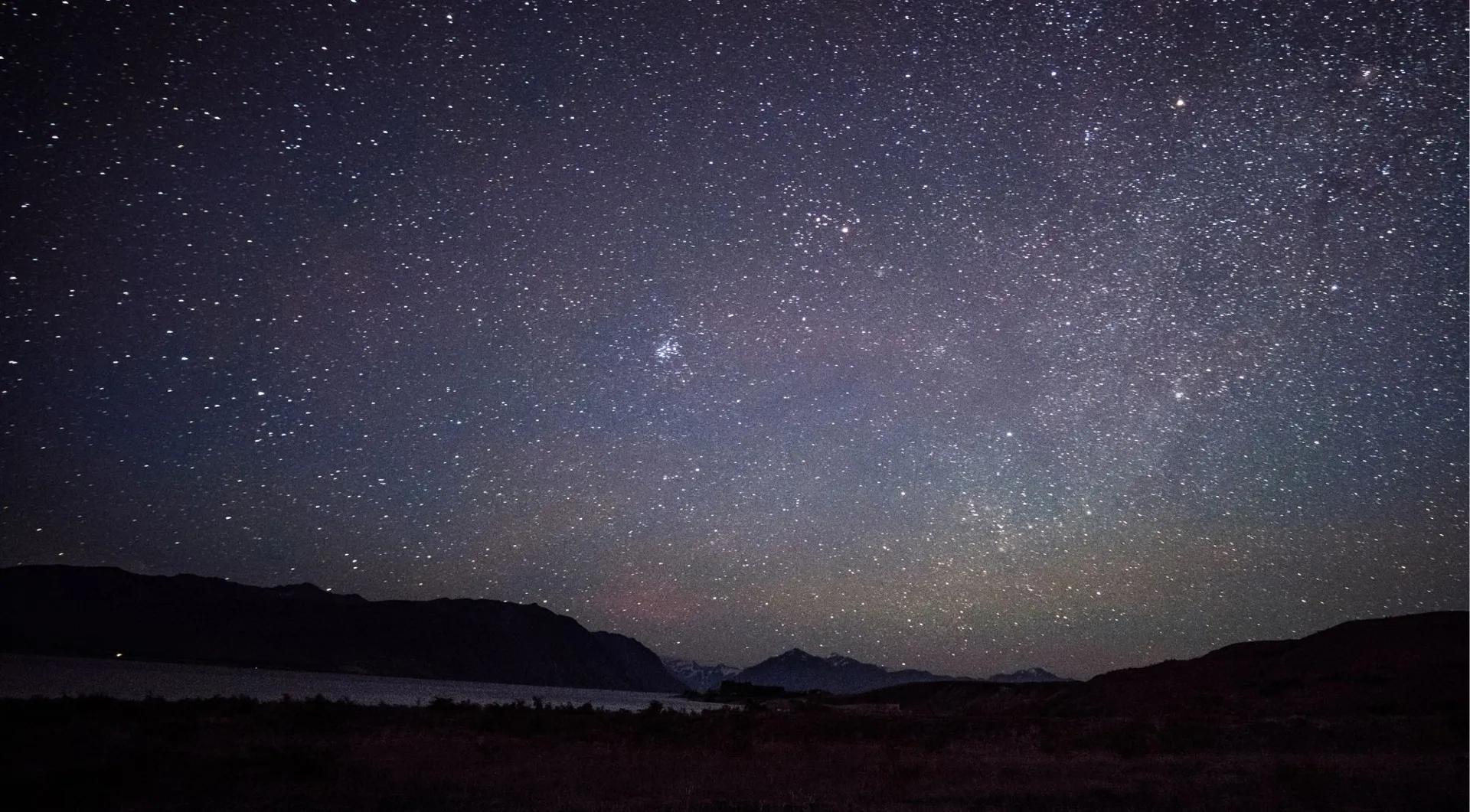 Stars above a dark mountain horizon